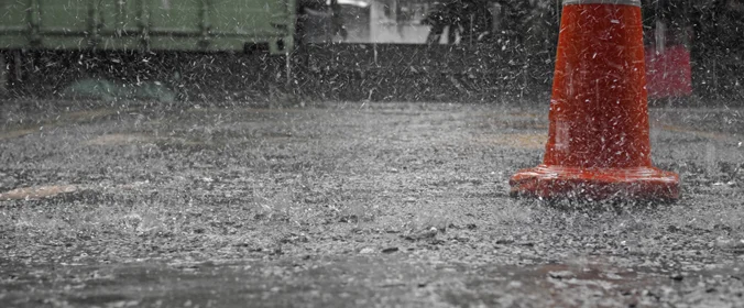 foto de um cone no chão, alagado, por causa da chuva